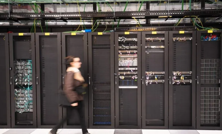 Woman walks past rows of server racks in a data center.