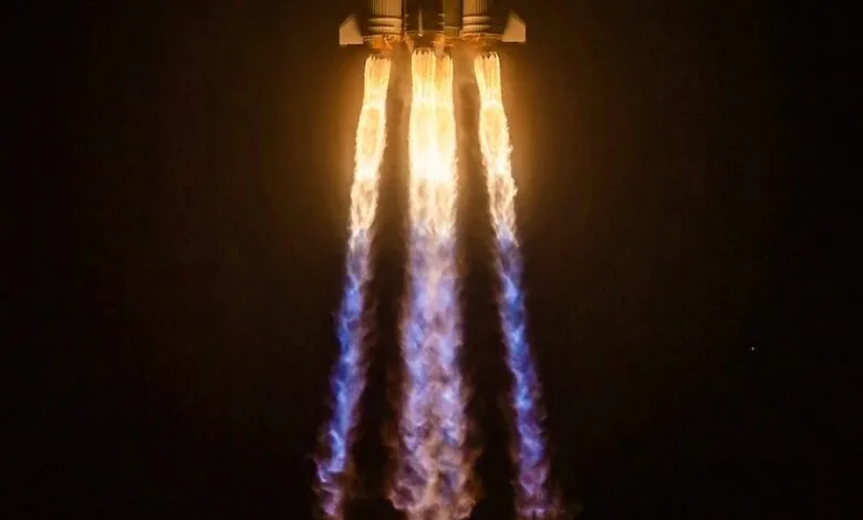 Rocket launching with bright flames against a dark sky.