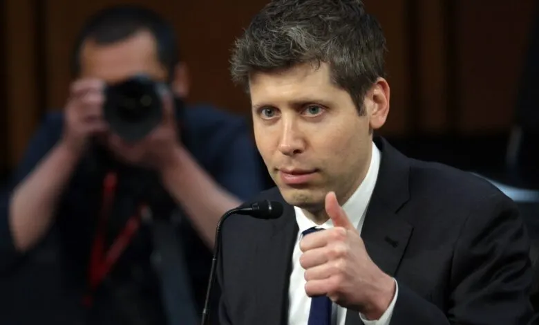 Man in suit gives thumbs up at microphone, photographer in background.