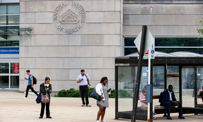 People wait at a bus stop outside the National Institutes of Health building.