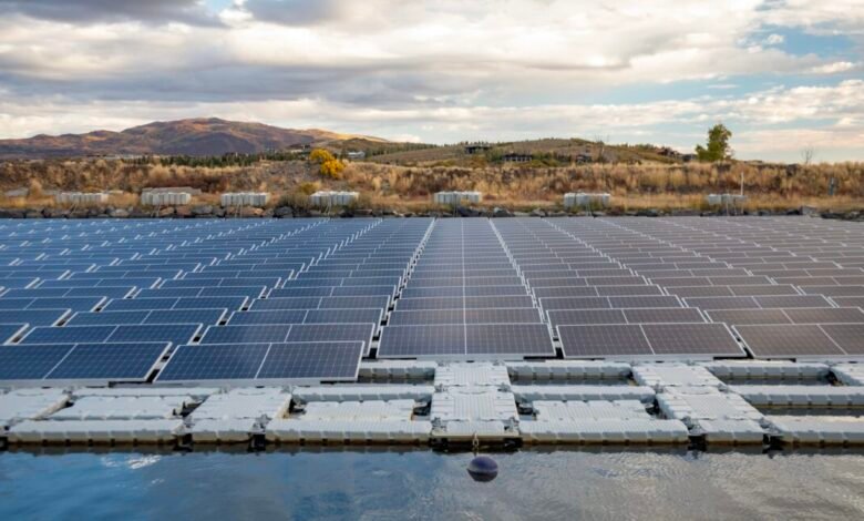 Floating solar panels on a pond with hills and cloudy sky in the background.