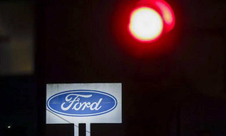 Ford logo sign illuminated at night with a red light above.