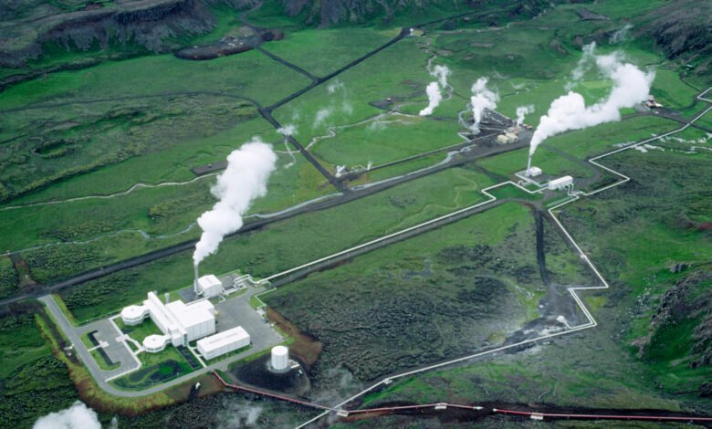 Aerial view of a geothermal power plant with steam rising from multiple stacks.