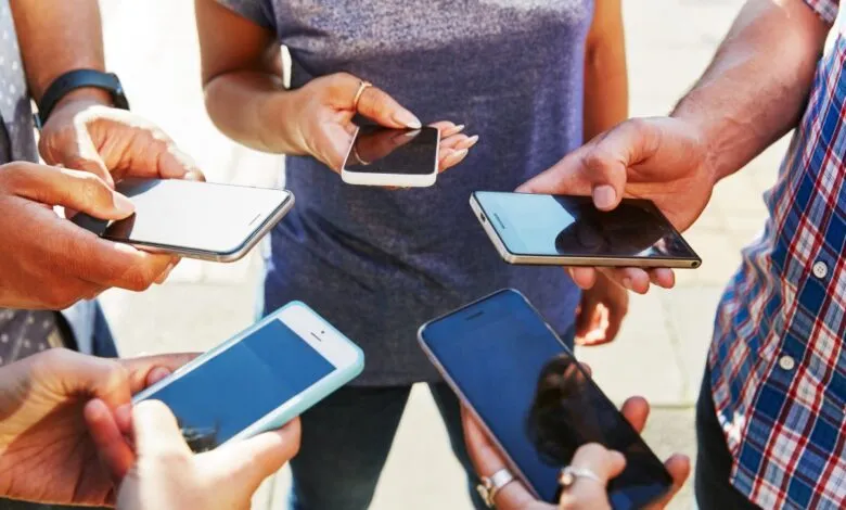 Group of people holding and looking at their smartphones.