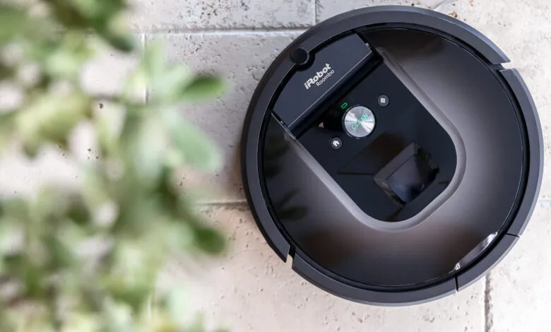 Overhead shot of a black iRobot Roomba on a textured tile floor.
