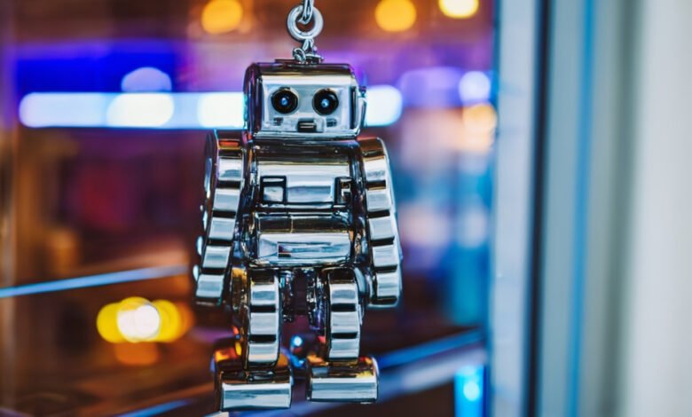 Shiny silver robot toy hanging from a chain, blurred background.