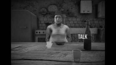 Black and white scene shows a man at a table with a bottle labeled 'TALK'.