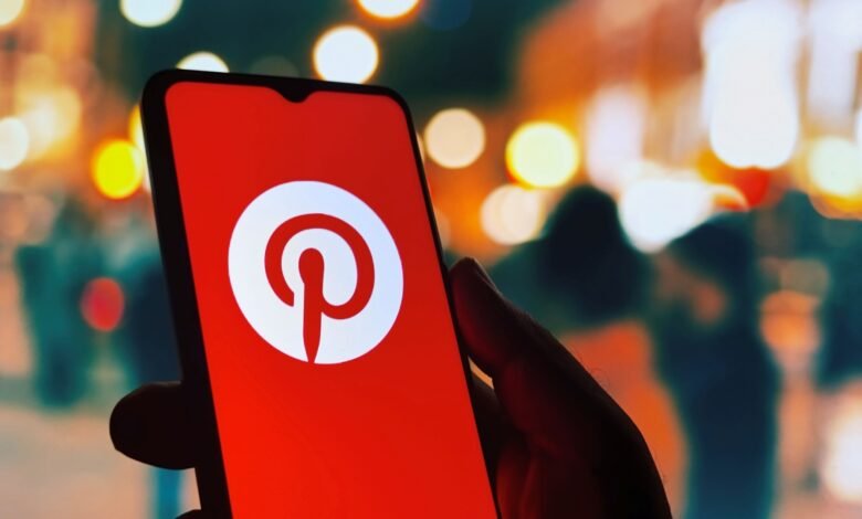 Hand holding smartphone displaying the Pinterest logo.