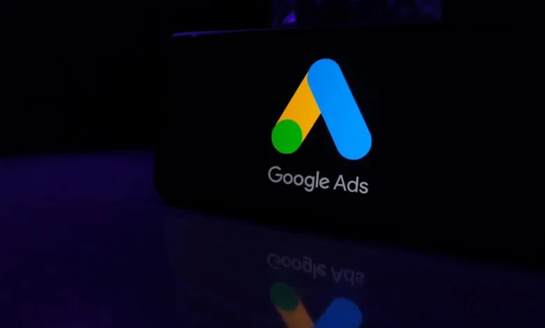 Google Ads logo on a dark screen, reflecting on surface.