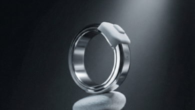 Silver smart ring with white sensor on stack of smooth, gray stones.