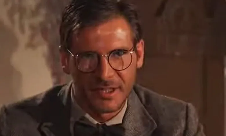 Harrison Ford as Indiana Jones wearing glasses and a suit.