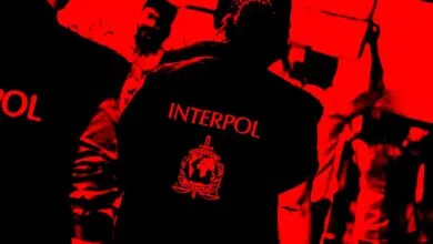 Interpol officers in black uniforms with red lettering and logo.