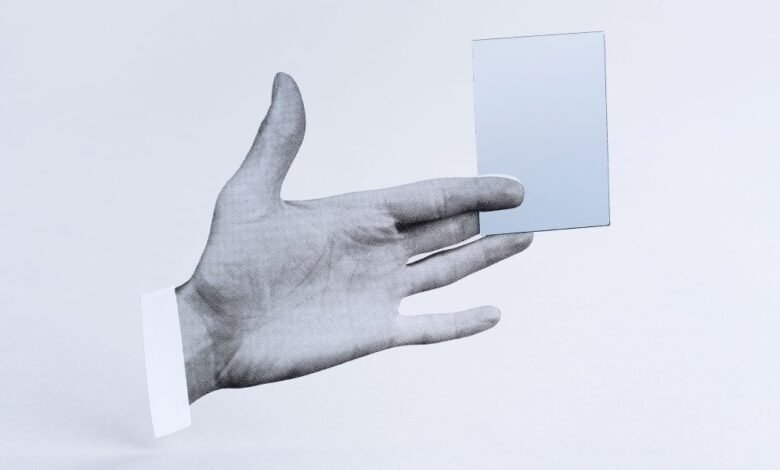 Monochrome hand holding a reflective card against a white background.