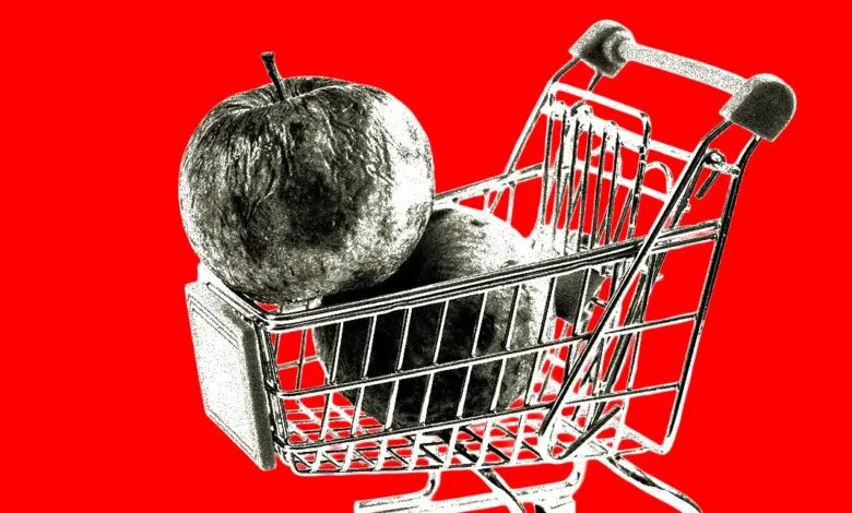 Monochrome apples in a silver shopping cart against a vibrant red background.