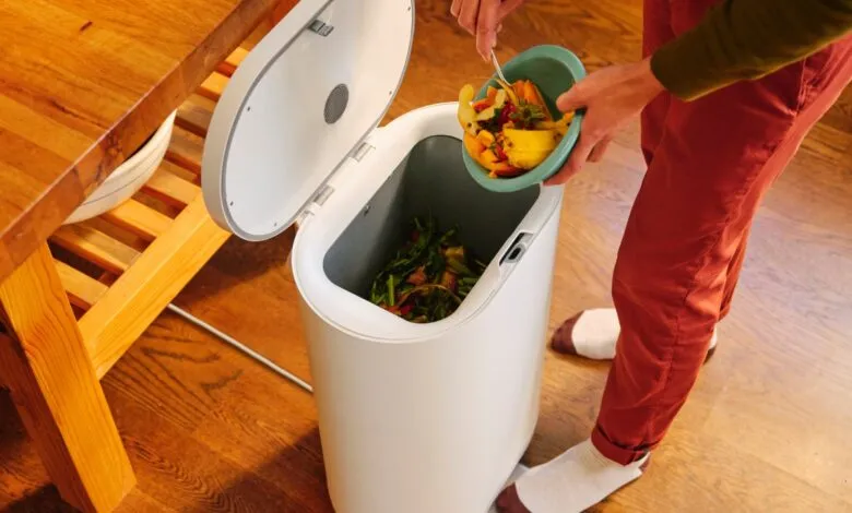 Person emptying food scraps into a white kitchen composter.
