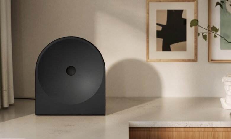 Modern black speaker on a countertop with art and a bust candle.