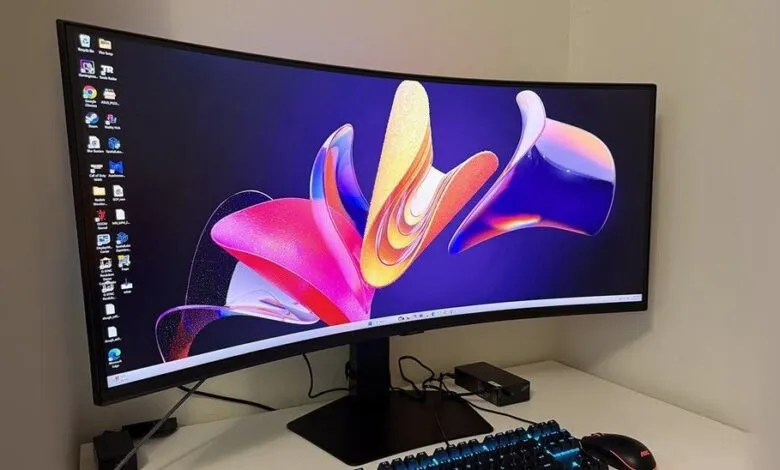 Curved monitor displaying colorful abstract wallpaper, keyboard and mouse visible.