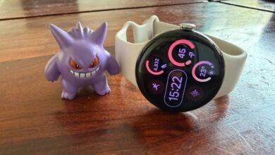 Google Pixel Watch with Gengar figurine on a wooden surface.