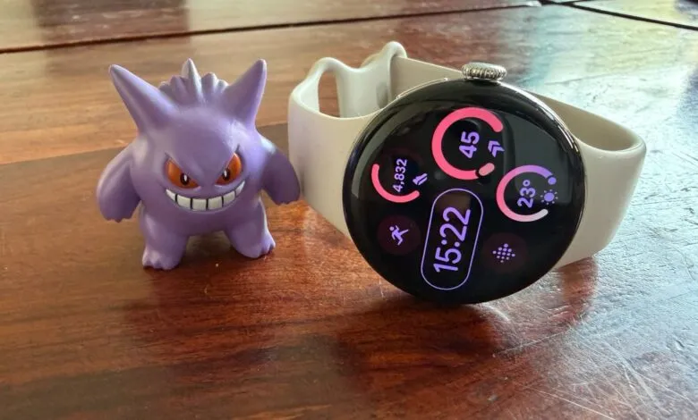 Google Pixel Watch with Gengar figurine on a wooden surface.