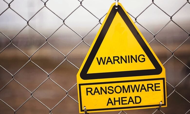Yellow warning sign on fence reads 'WARNING RANSOMWARE AHEAD'.