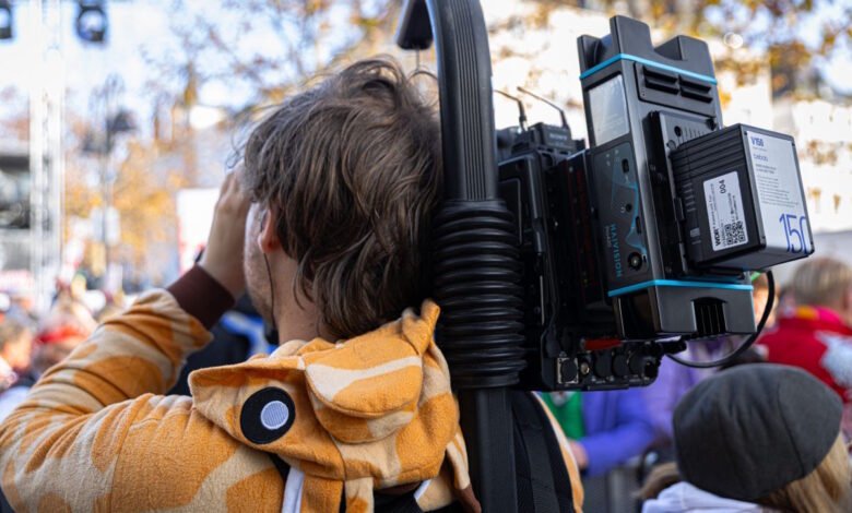 Cameraman in giraffe costume carries Haivision camera rig at outdoor event.