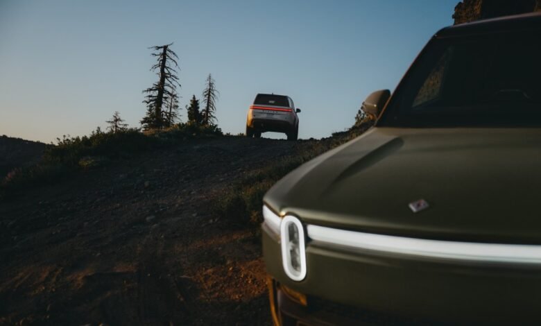 Two Rivian electric trucks on a dirt road, one in the foreground.