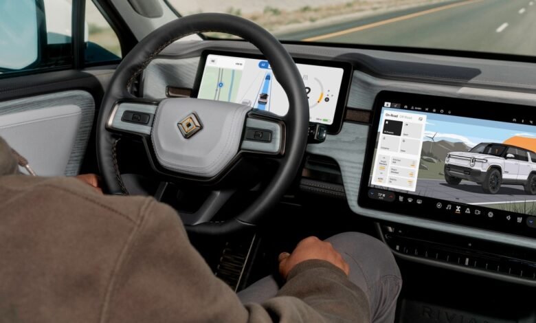 Interior view of Rivian electric vehicle showing dashboard screens and steering wheel.