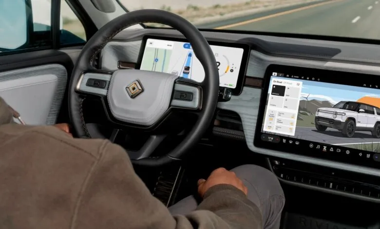 Interior view of Rivian electric vehicle showing dashboard screens and steering wheel.