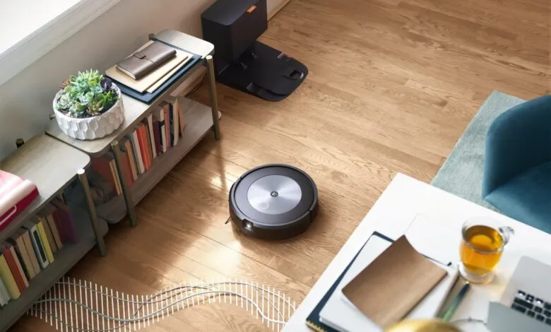 Roomba robot vacuum cleaning hardwood floor in a modern living room.