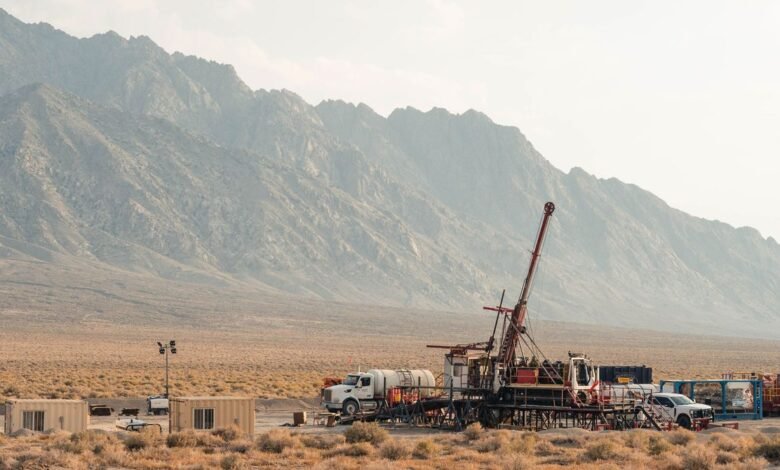 Geothermal drilling rig in desert landscape with mountains in background.