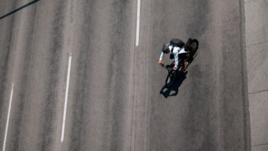 Aerial view of cyclist with backpack riding on asphalt road.