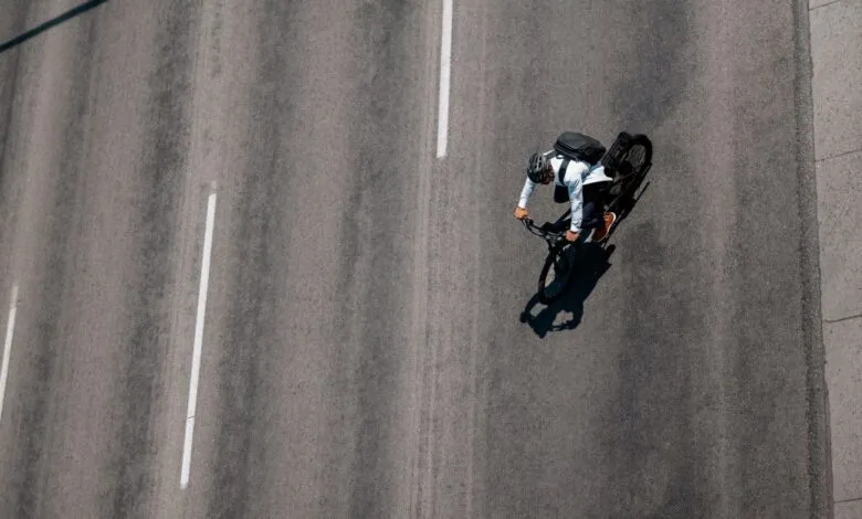 Aerial view of cyclist with backpack riding on asphalt road.