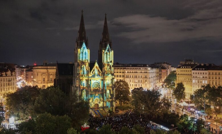 Illuminated church at night with large crowd gathered in front.