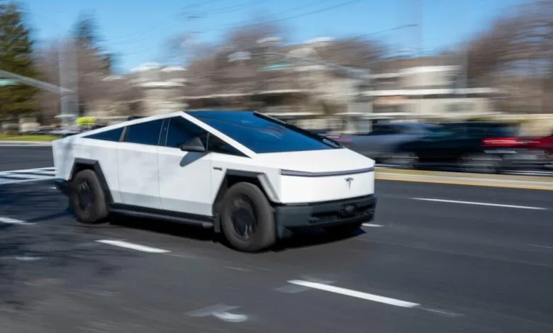 White Tesla Cybertruck driving on road with blurred background.
