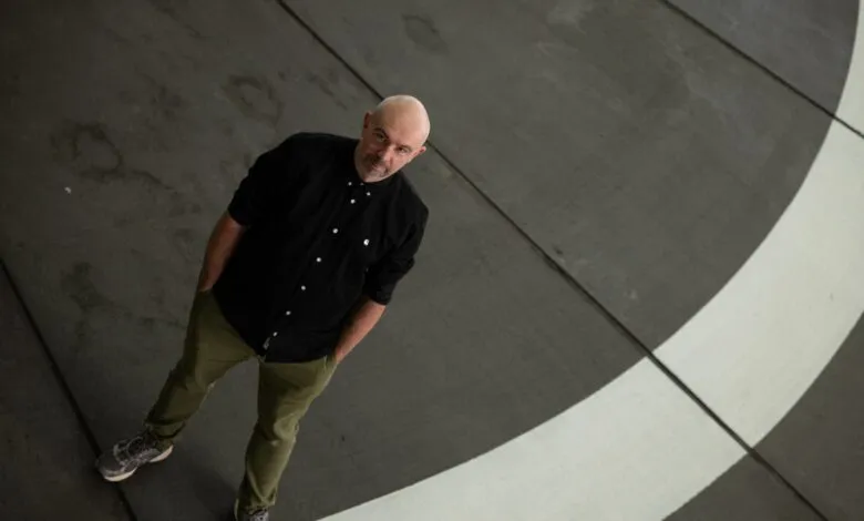 Man in black shirt and green pants stands on painted surface.