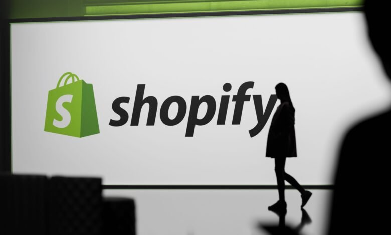 Shopify logo on screen with silhouetted person walking by.