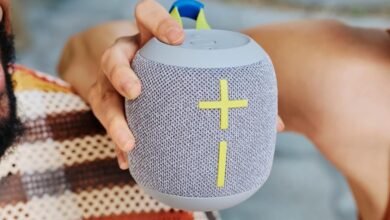 Person holding a gray Ultimate Ears Wonderboom speaker with yellow accents.