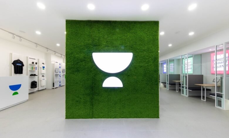 Unacademy logo on a green wall in a modern office space.