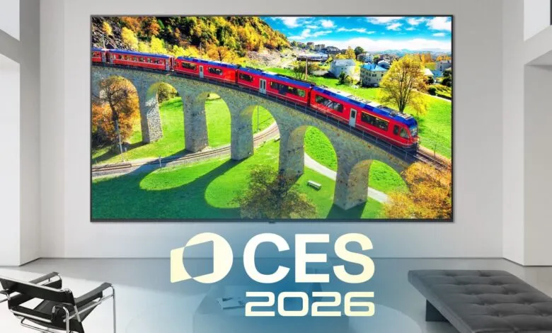 Large screen TV displaying a red train crossing a stone bridge in a scenic landscape.