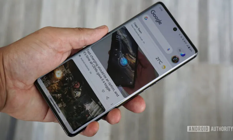 Hand holding smartphone displaying Google Discover feed with news articles.