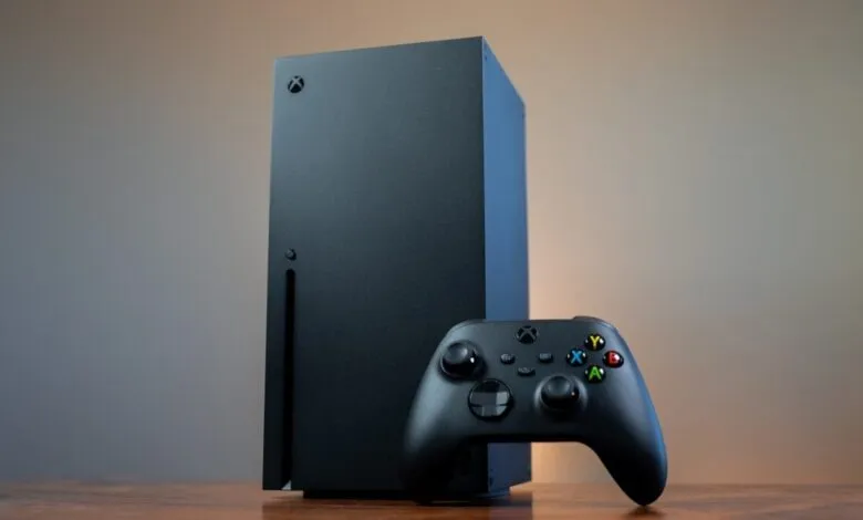 Xbox Series X console and controller on a wooden surface.