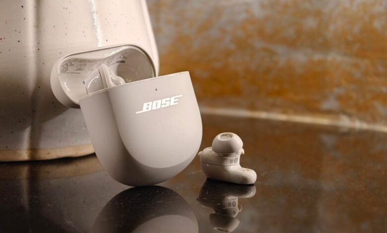 Bose QuietComfort Ultra Earbuds with charging case on reflective surface.