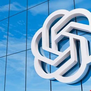 OpenAI logo on glass building reflecting blue sky and clouds.