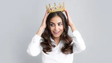 Woman with crown on head, smiling and looking to the side.