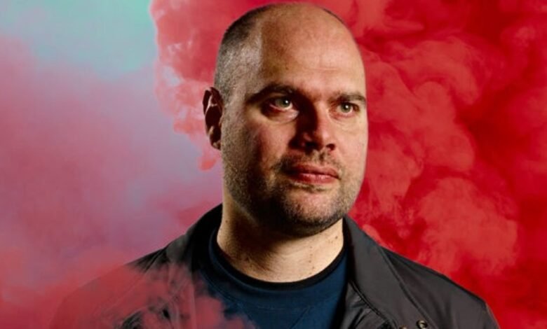 Portrait of David Grivel against a red and teal smoky background.