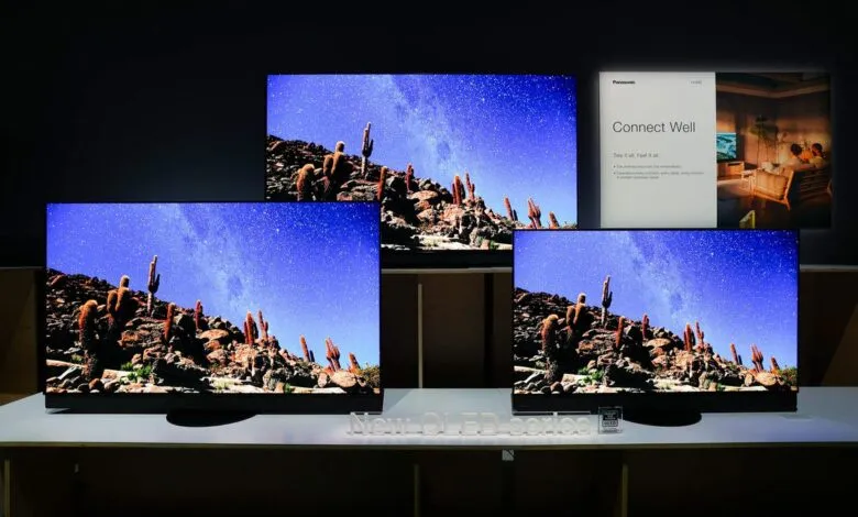 Three Panasonic OLED TVs display a desert landscape under a starry night sky.