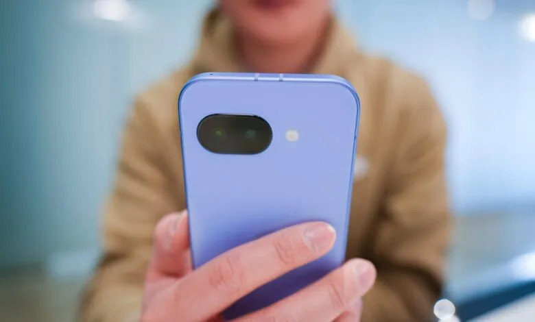 Person holding a light purple smartphone with dual camera lens.