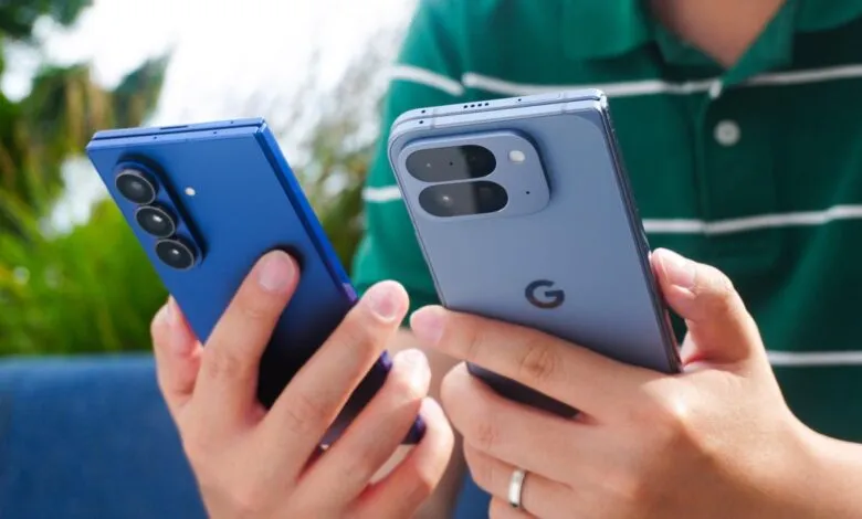 Person holding blue Google Pixel Fold and Pixel 8 Pro smartphones.