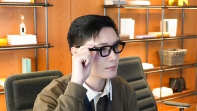 Person wearing black-framed glasses in an office setting.