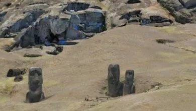 Moai statues stand on Easter Island against a rocky hillside.